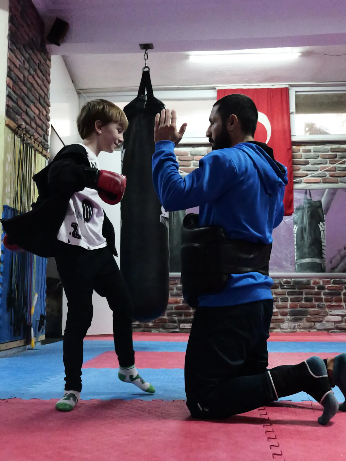 Young student practising kicks with Coach Ali