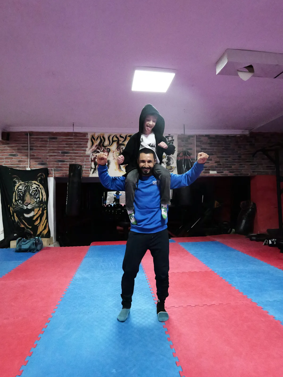 Coach Ali lifting a young student in the gym